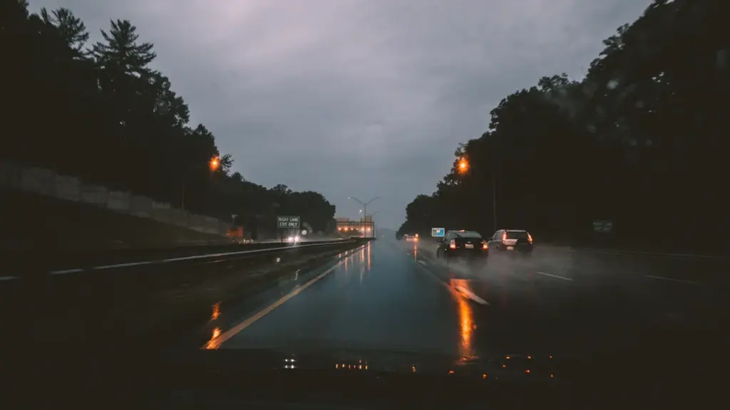 Cars driving on a wet motorway during a dark and rainy day.