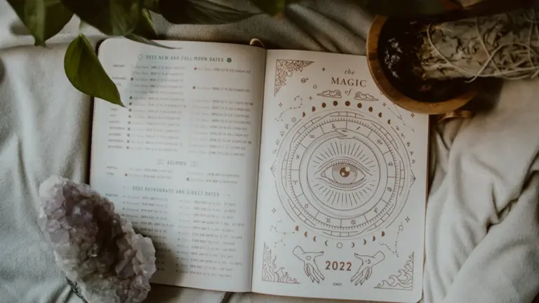 An open journal page with astrological diagrams and a crystal on fabric.