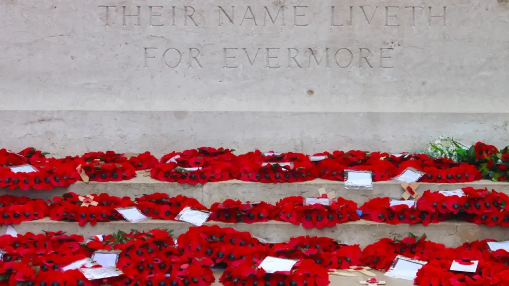 British war memorial with red poppy wreaths on concrete steps in the UK.
