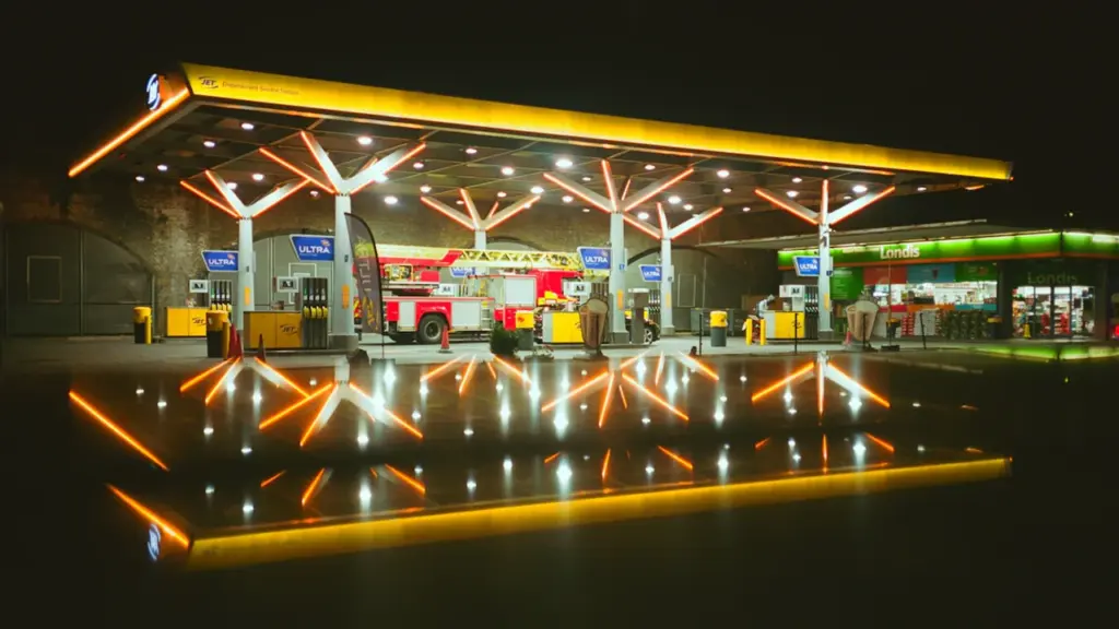Vibrant nighttime view of a modern illuminated British petrol station forecourt.