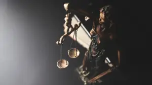 Statue of Lady Justice holding golden scales against a dark moody background.