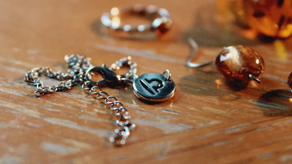 Close up of a silver Libra zodiac pendant resting on a wooden table.
