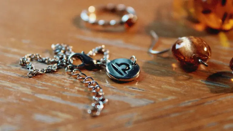 Close up of a silver Libra zodiac pendant resting on a wooden table.